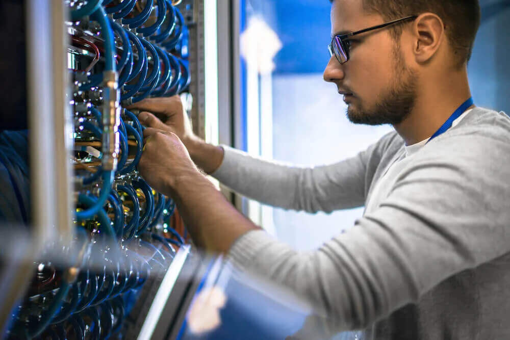 IT technician fixing server farm with network cables